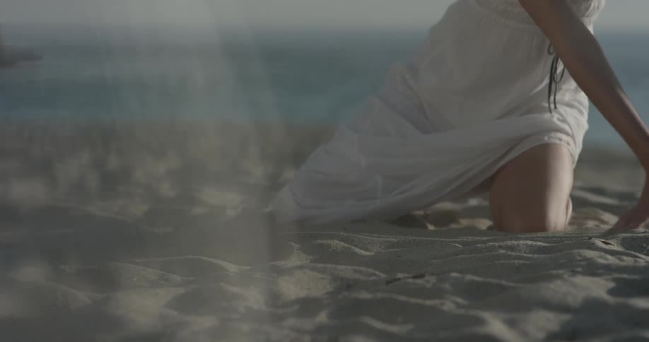 A woman rubs her hands in the sand