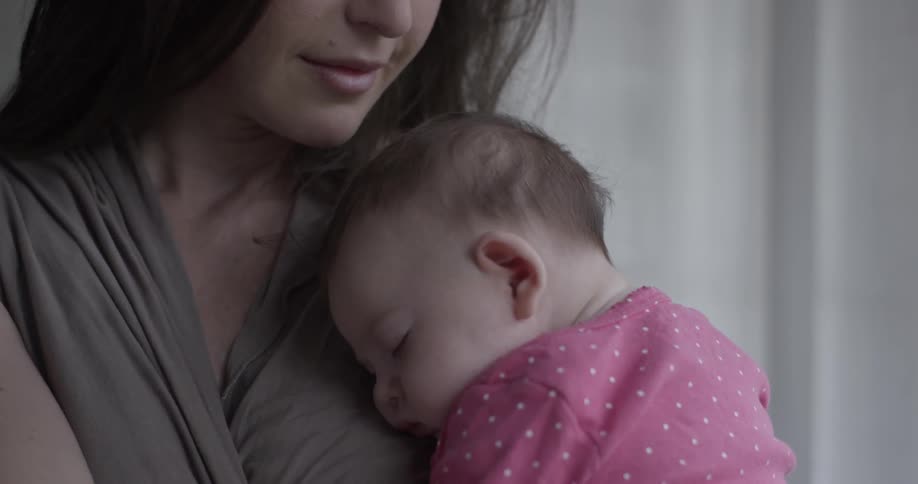 Woman holds baby and looks out of window then down toward child