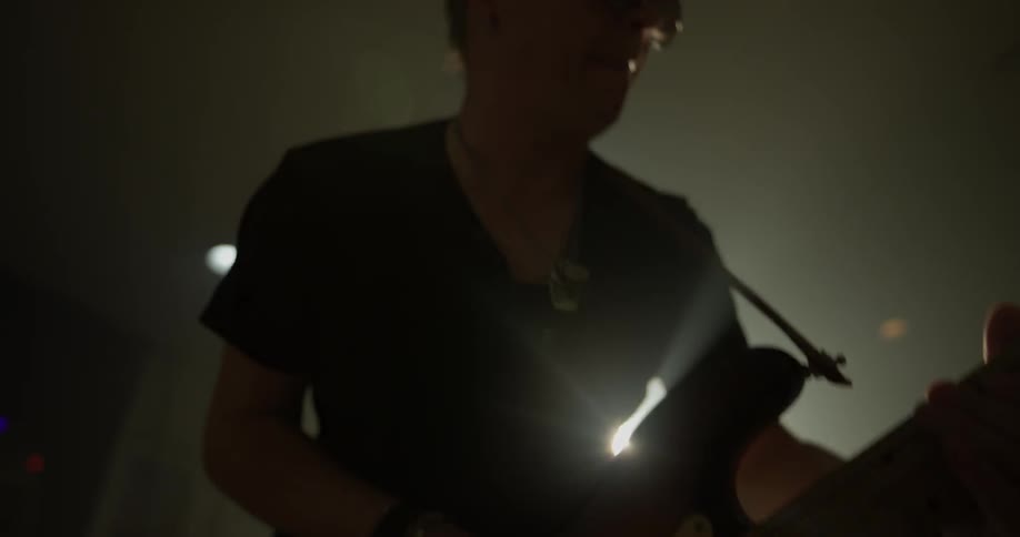 Man plays guitar in dimly lit room