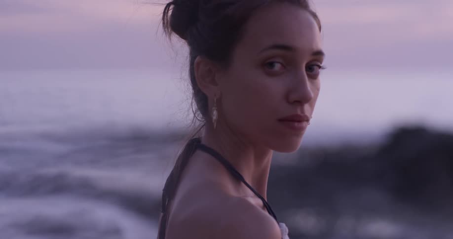 A woman standing on a seashore looking around