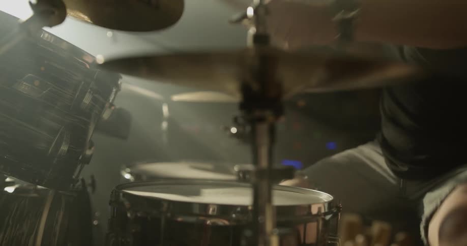 A man plays the drums in a dark room
