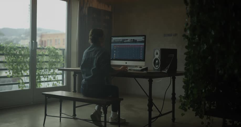 A woman working on a computer with large speakers in a rustic office