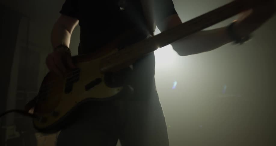 Person plays bass guitar in room with bright white light
