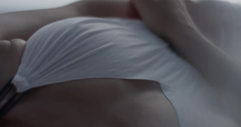 A woman caresses herself while laying under the sun