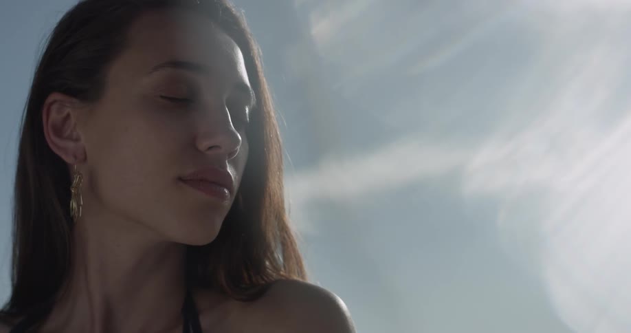 A woman is outside and closing her eyes