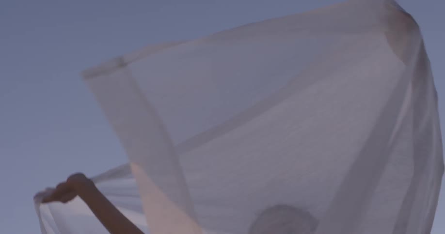 Woman sways as she flutters a white sheet over her head
