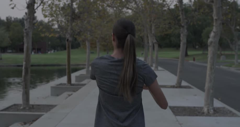 Woman stretches and swings her arms while walking on the sidewalk and listening to music