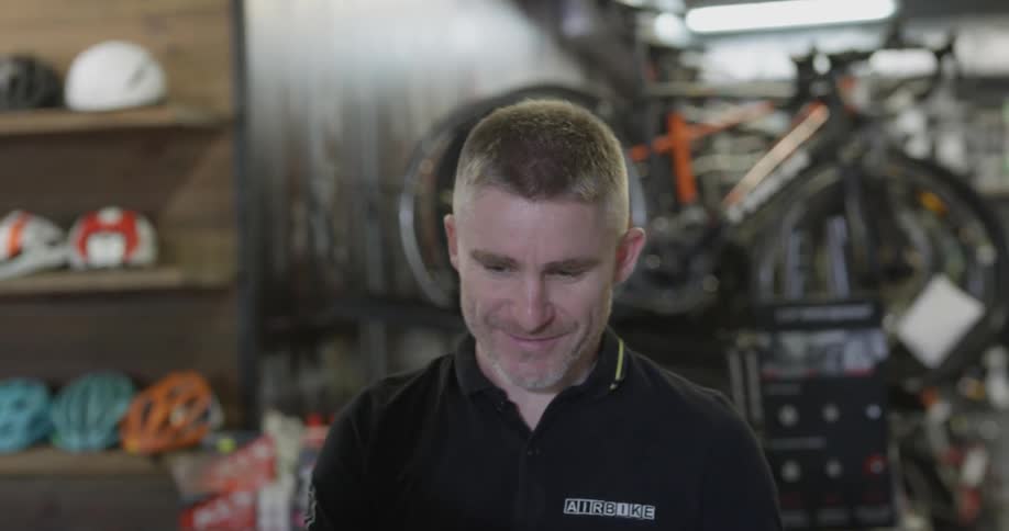 A bicycle shop employee scans a customers phone and hands them a receipt