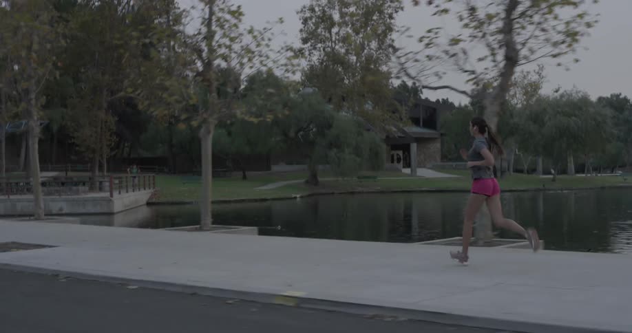 Woman runs on the sidewalk beside a lake