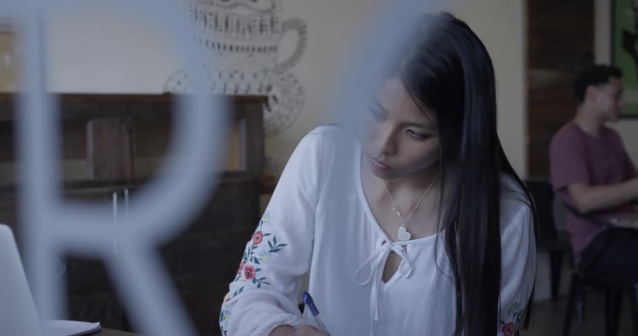 Woman copies something from laptop onto paper