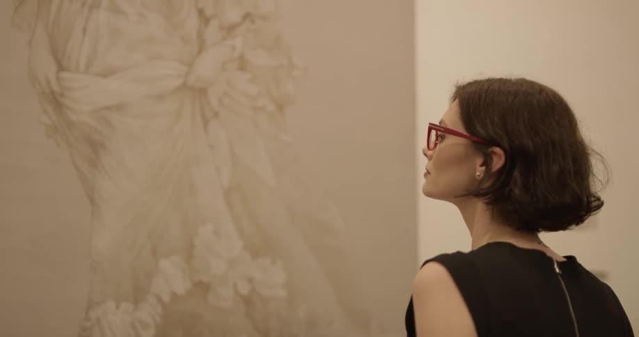 A woman wearing glasses is looking at a drawing