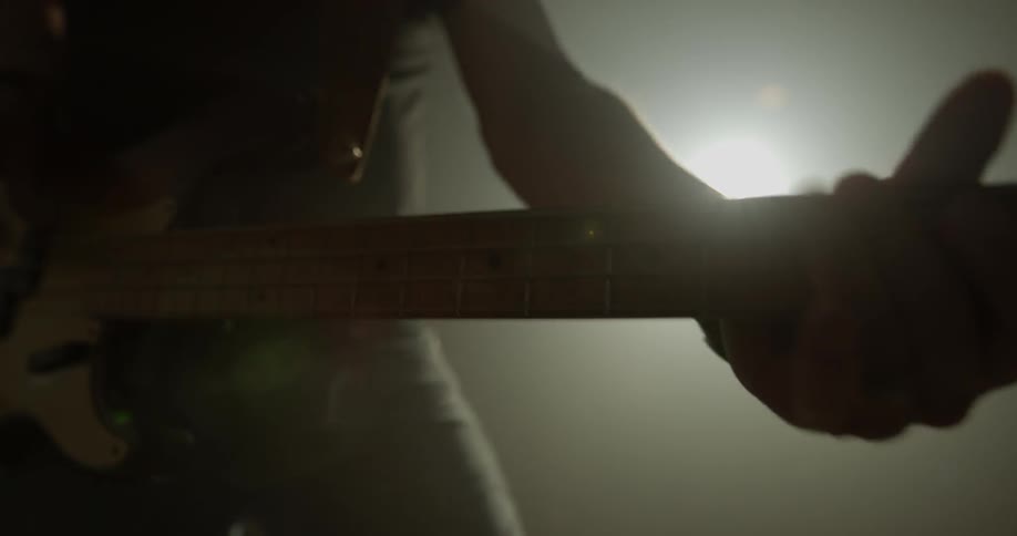 A person plays an electric guitar in front of an amplifier