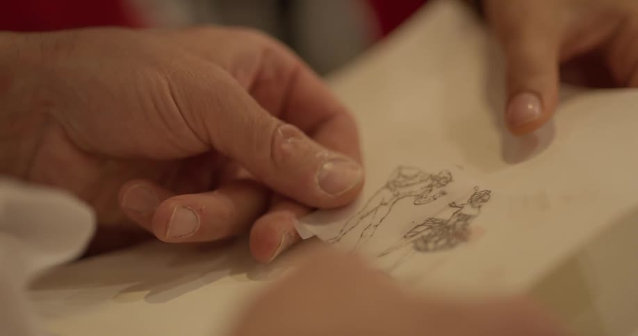 A person looks at small drawing on paper