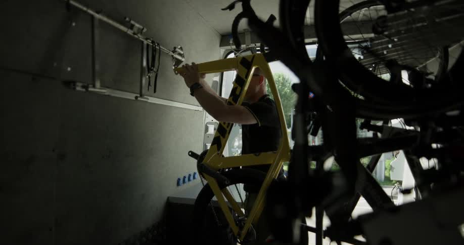 A man places the frame of a bicycle inside a large vehicle