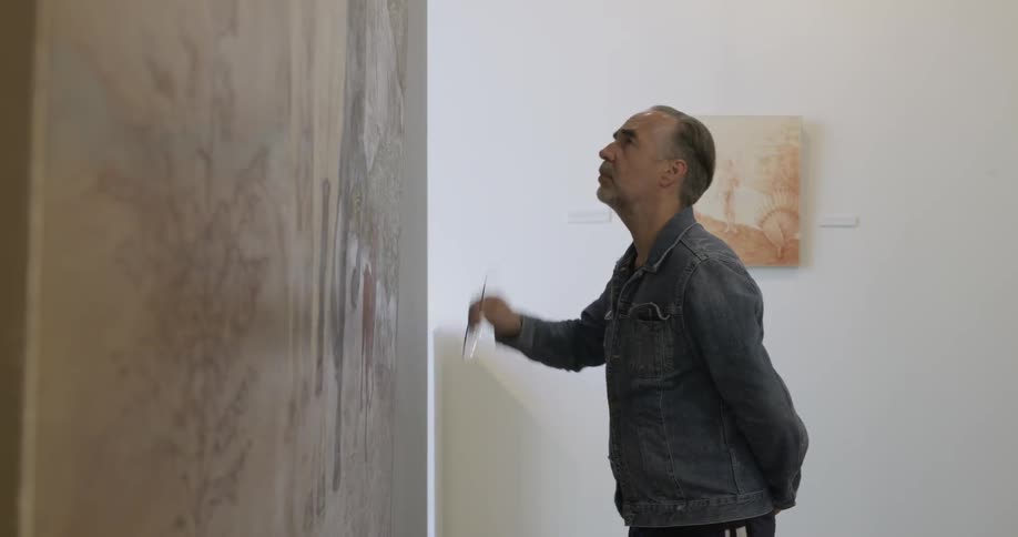 A man puts glasses on to look at art