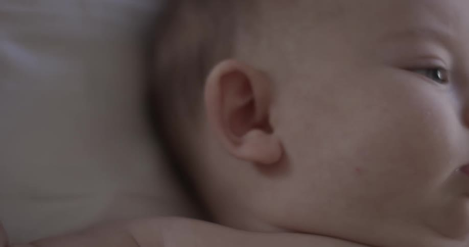 A baby moves its head around and spits up a little