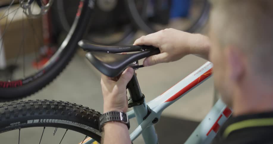 A man attaches a seat to a bicycle