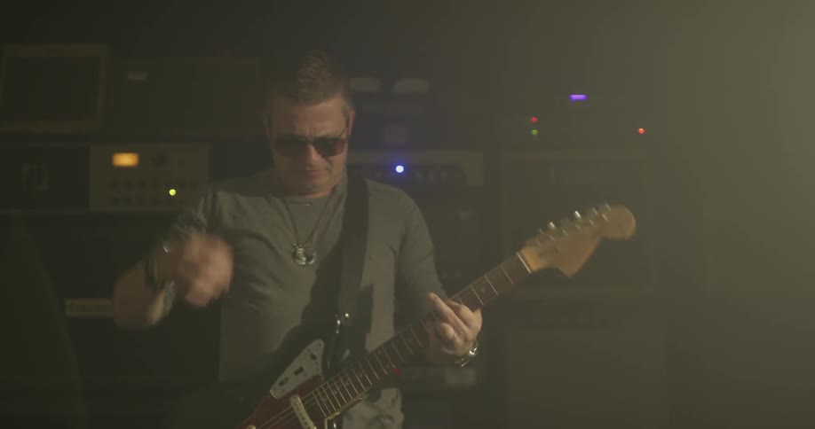 A man in sunglasses plays an electric guitar on stage during a concert
