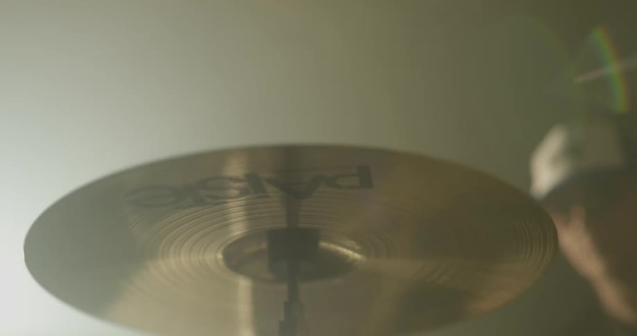 Man drums on a large drum set in a bright room