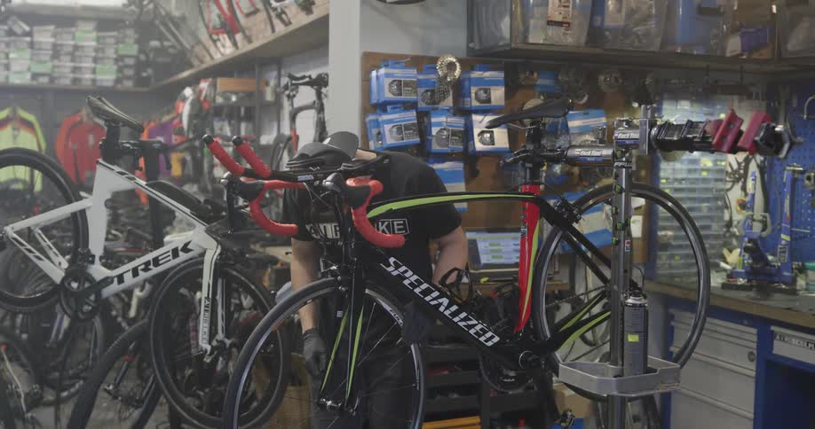 Man spins and adjusts wheel of bicycle in bicycle shop
