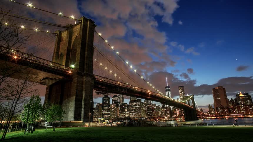 A bridge and city skyline goes from day to night