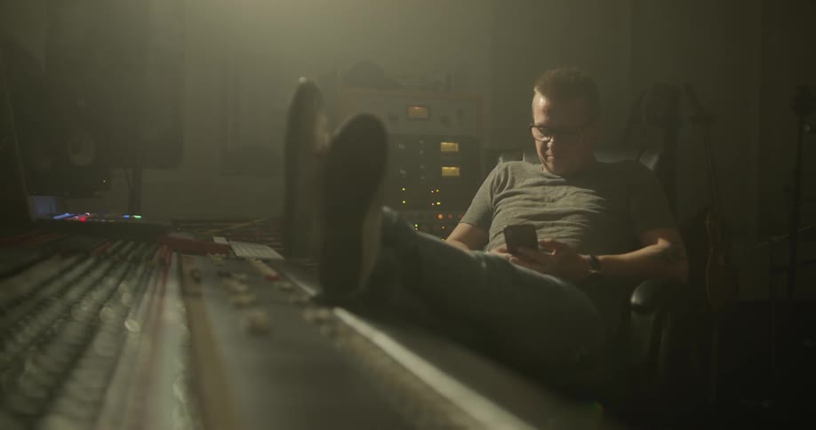 A man sitting in a studio looking at his phone
