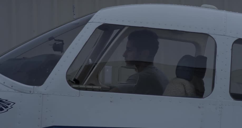 A man flips switches in the cockpit of an airplane