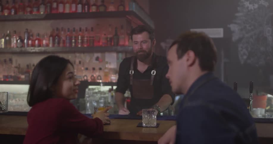 Two people are sitting at a bar drinking