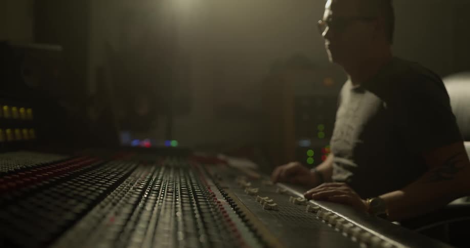Man touches button on sound board and taps his fingers