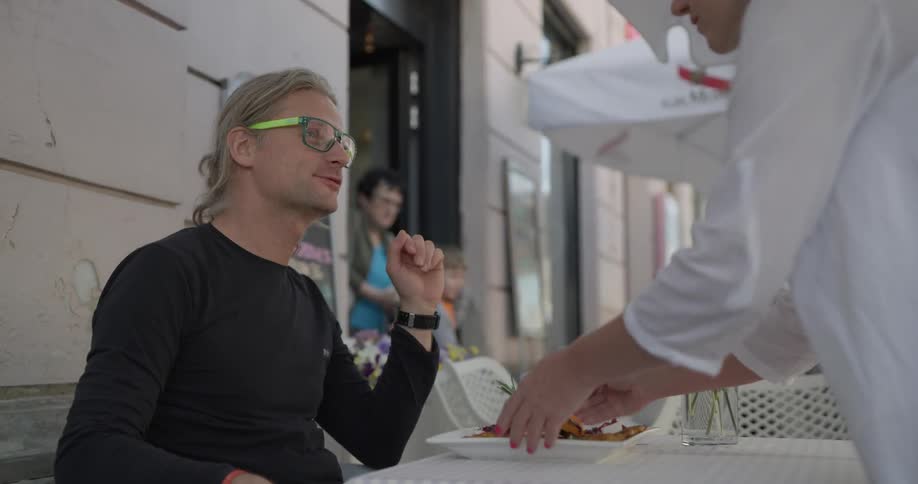 Food is being served to a man wearing glasses
