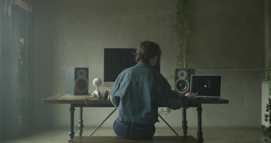 Woman sitting at desk opens laptop and turns it on