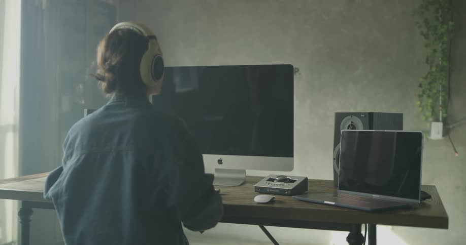 Woman wears headphones and uses keyboard and mouse