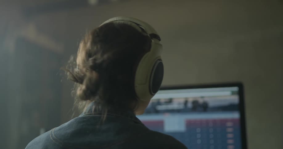 Woman wearing headphones sits in front of a computer monitor