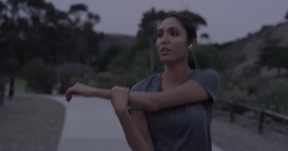 A woman walking in a park stretching her arms