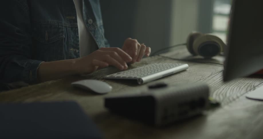 Woman types on a desktop keyboard then moves to the mouse