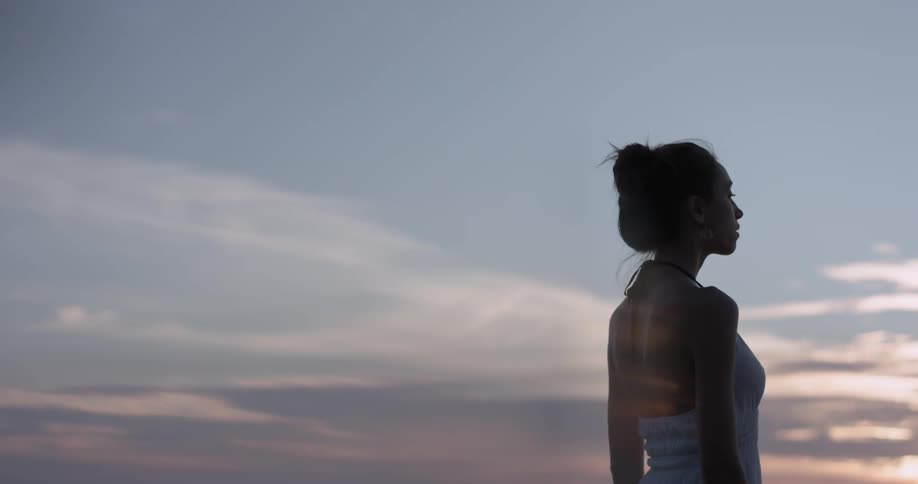 Woman stands outside gazing toward the horizon