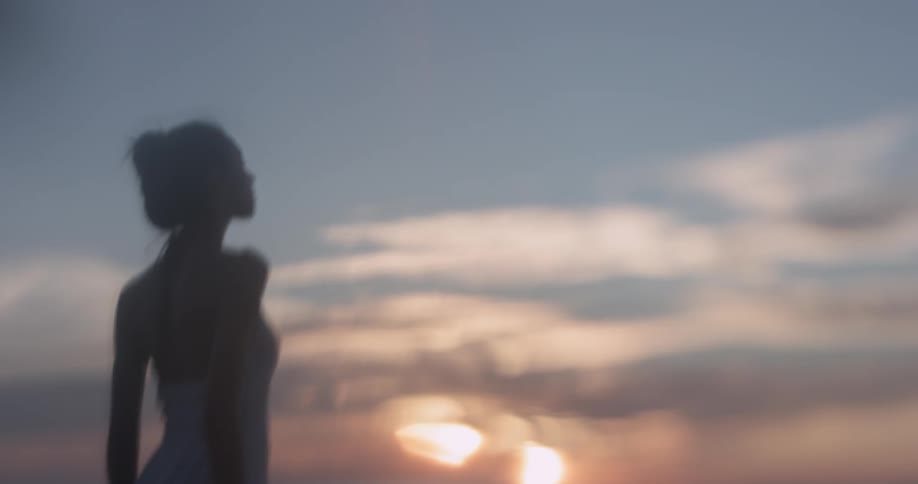 Woman with hair up standing outside at sunset looking into the sky