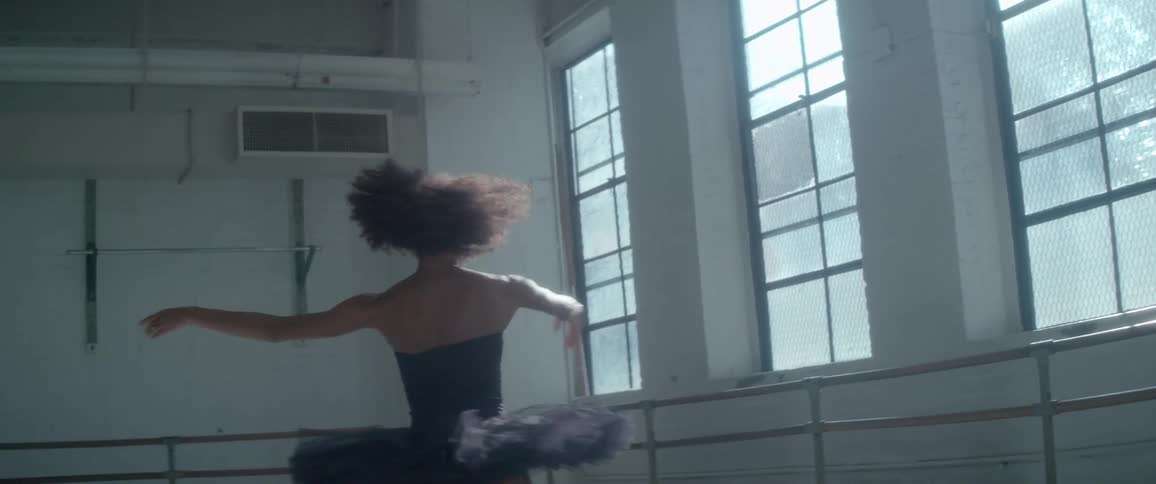 Woman in a black tutu pirouetting in a ballet studio