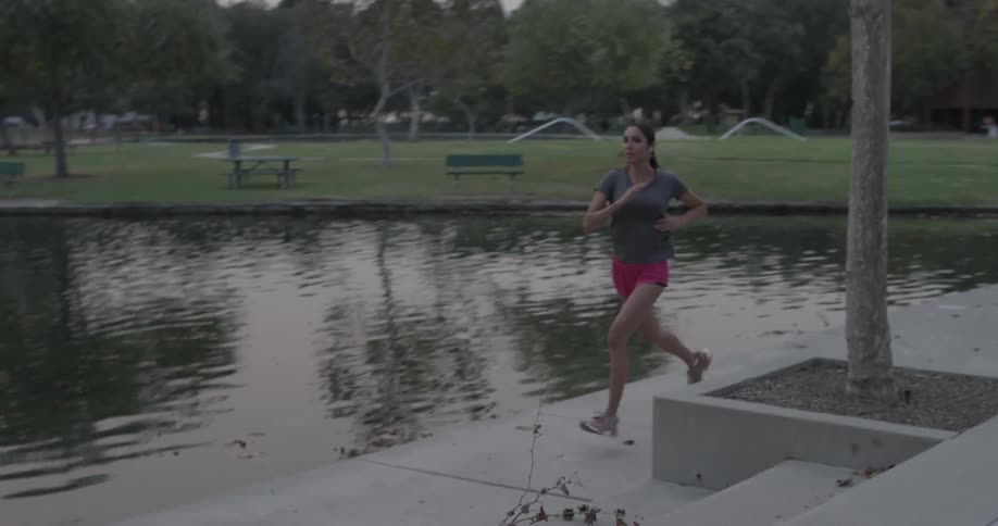 A woman is jogging outside by a park