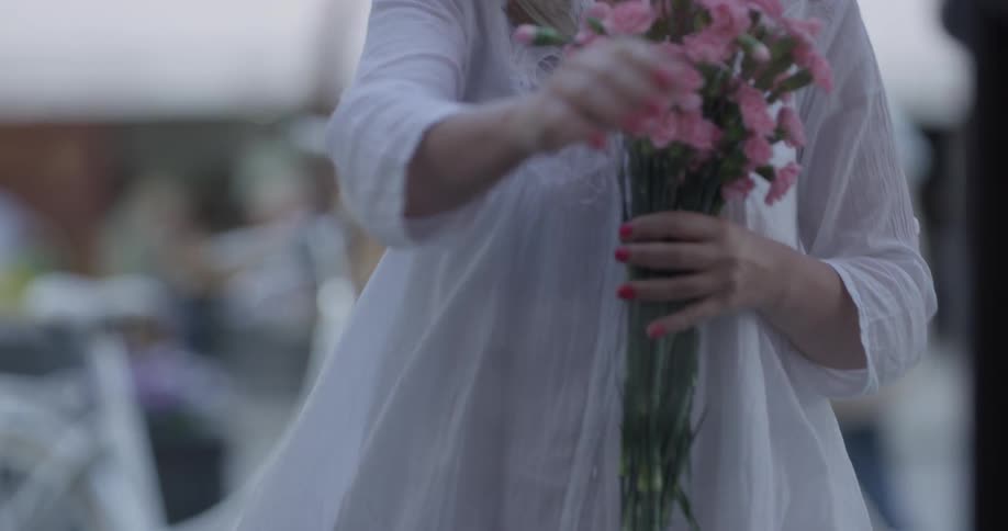 A woman is holding flowers and walking indoors