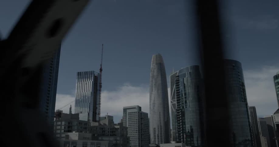 Car on a bridge passes the supports while we view a city in the background