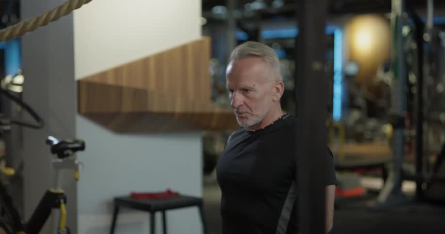 Man lifts weights in a gym while sitting