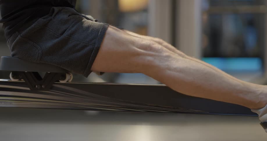 A man sits on workout equipment at the gym and exercises with repetition