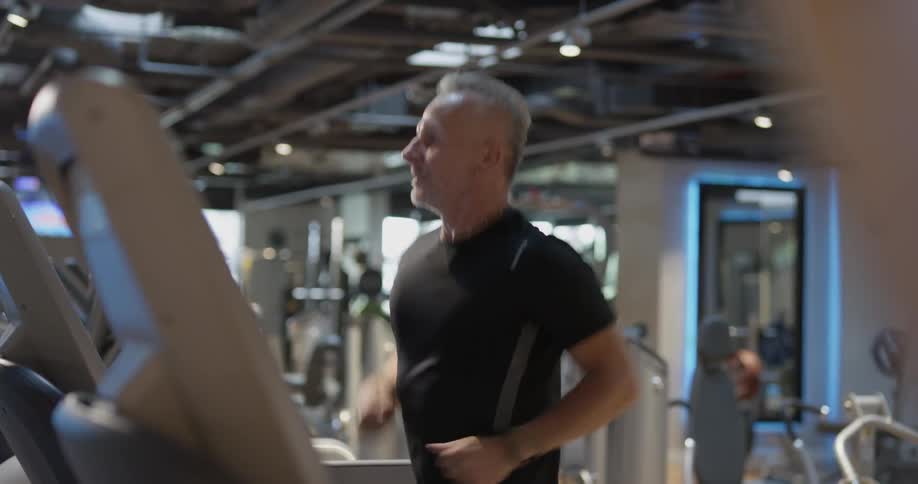 Man in gym runs on treadmill