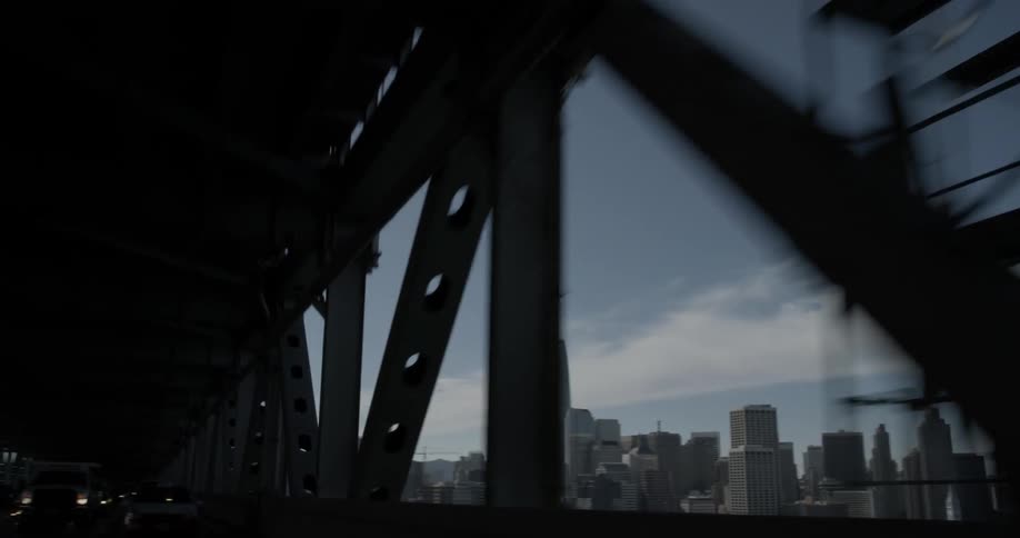 Riding in a car one sees the bridge iron works pass by and the city in the background