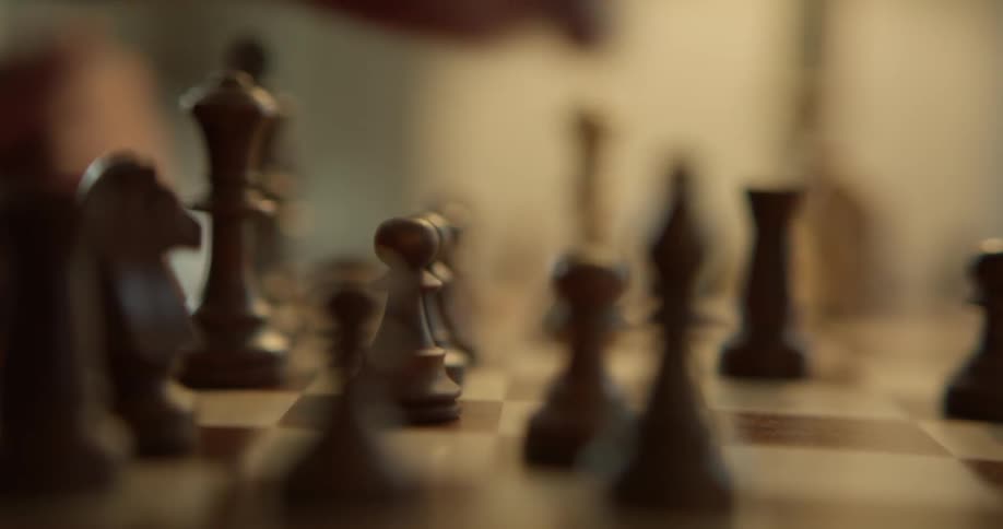 A person moves a white bishop on a chess board