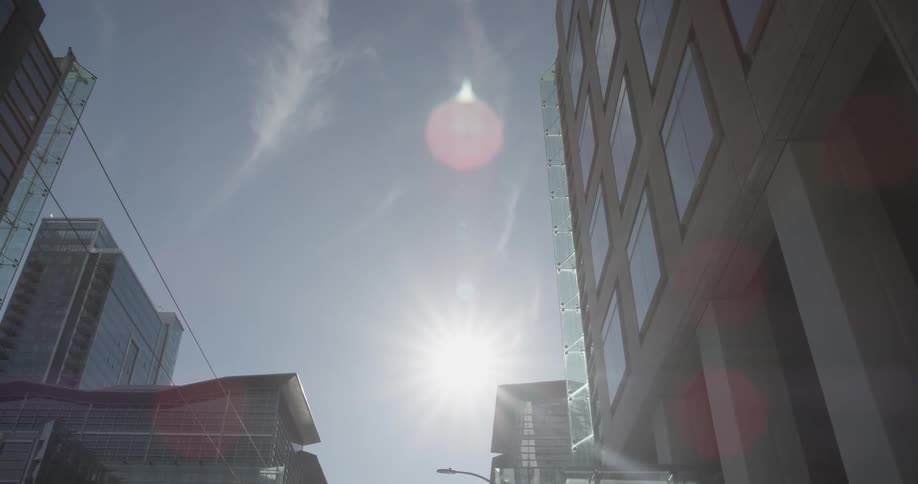 The sun is high in the sky by buildings