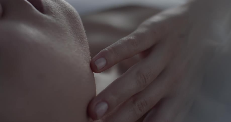 A woman laying on her back runs her fingers along her collar bone