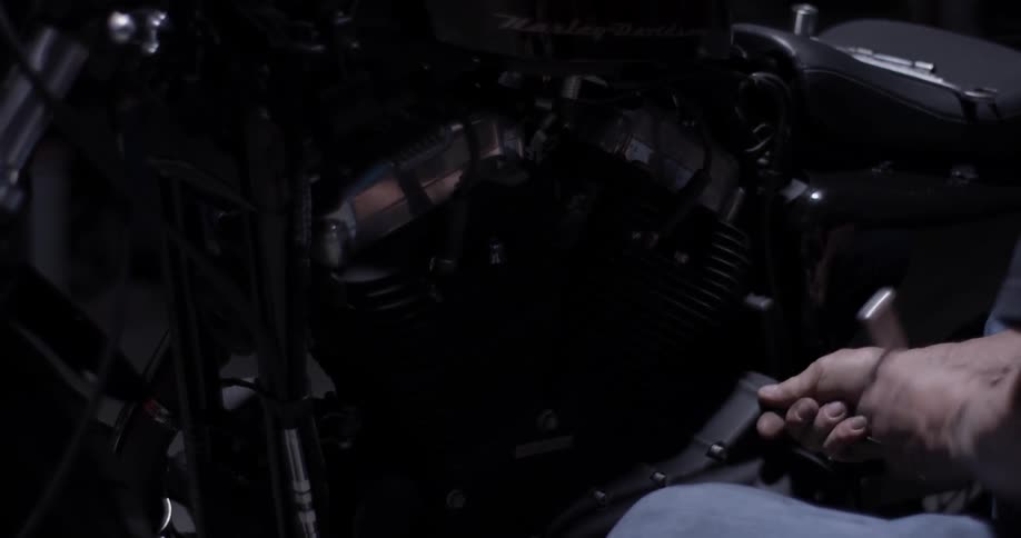 A man uses a ratchet on a motorcycle