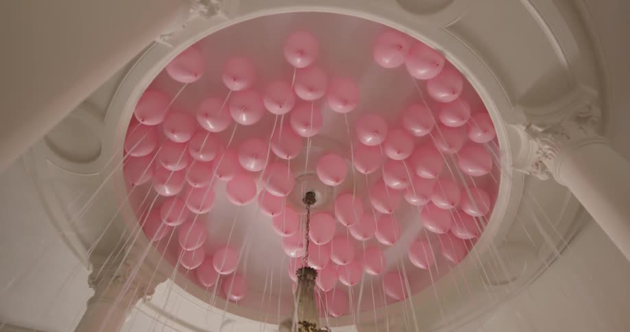 Pink helium balloons pinned against a ceiling